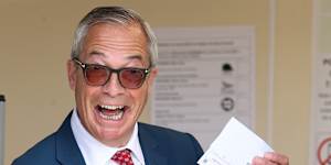 Britain’s Reform Party leader Nigel Farage poses with his poll card at a polling station.