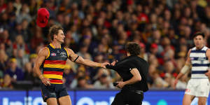 Adelaide’s Matt Crouch takes hold of a pitch invader in the third quarter against Geelong.