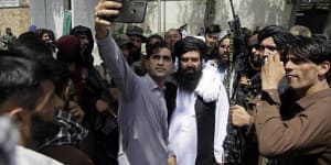 An Afghan takes a selfie with Taliban fighters on patrol in Kabul on Thursday.