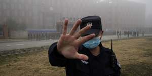 A security person moves journalists away from the Wuhan Institute of Virology in February 2021.
