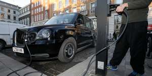 A London cab driver charges a TX City London taxi built by the London Electric Vehicle Company.