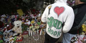 A Sandy Hook resident wears a handmade sweatshirt in support of his town while looking at a memorial to the Newtown shooting victims in the Sandy Hook village of Newtown,Connecticut.