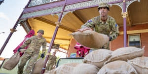 Members of the armed forces remove sand bags from businesses in the main street of Rochester.