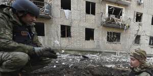 Police officers inspect a crater in front of a damaged residential building hit by a Russian strike in Kharkiv,Ukraine,on Wednesday. 