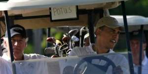 President Barack Obama steers a golf cart with his golfing partner,Vice President Joe Biden