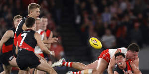 Essendon’s Jye Caldwell gets a handball away under a crunching tackle.