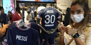 A PSG fan poses with the Argentine star’s new shirt at the club’s official store.