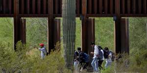 A group of people claiming to be from India walk past open border wall storm gates after crossing through the border fence in the Tucson sector of the US-Mexico border in Organ Pipe Cactus National Monument near Lukeville,Arizona,in late August.