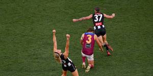 Darcy Moore raises his arms in the air to celebrate Collingwood’s win,while his opponent Joe Daniher is dejected on the final siren.
