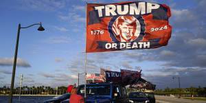 A supporter of Donald Trump raises a flag outside the former president’s Mar-a-Lago estate in Florida on Monday.