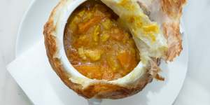 Peel back the lid of the chicken curry pot pie to reveal chunks of chook and vegetables.