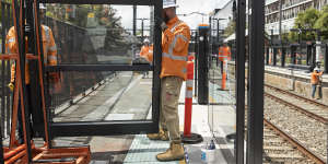 Workers install platform screen doors on platforms at Canterbury station for metro trains.