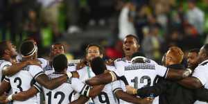 Fiji players and staff huddle together in celebration after winning the rugby sevens. 