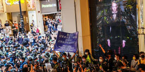 Riot police raise a blue flag inside a Hong Kong shopping mall warning people to disperse during a protest. 