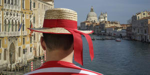 A gondolier surveys the Venice cityscape.