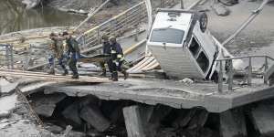 Ukrainian soldiers carry a body of a civilian killed by the Russian forces over the destroyed bridge in Irpin close to Kyiv.