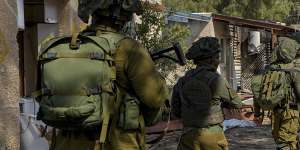 Israeli soldiers patrol next to houses damaged by Hamas militants in Kibbutz Kfar Azza,Israel.
