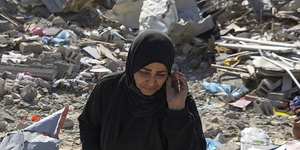 Manual Aslim walks through the rubble of her destroyed home in Rafah.