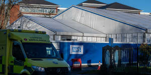 An ambulance passes a temporary structure,to be used as a surge hub for Omicron cases,in the grounds of St George’s Hospital in London.