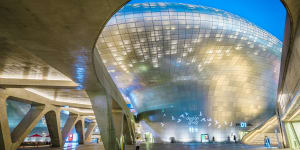 Dongdaemun Design Plaza - a Zaha Hadid-designed curving building of gleaming metal,lights up at night.