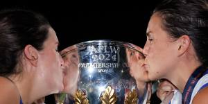 Bella Eddey and Libby Birch of the Kangaroos pose for a photo with the premiership trophy.