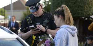 A woman speaks to police before laying flowers at the scene of the attack. 
