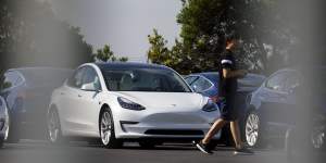 A person walks past a Tesla electric vehicle at the company's delivery center in Marina Del Rey,California.