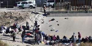 Migrants wait to cross the US-Mexico border from Ciudad Juárez,Mexico,next to US Border Patrol vehicles in El Paso,Texas on Wednesday,December 14.
