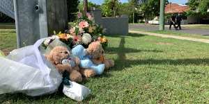 Floral tributes and teddy bears placed near the scene.