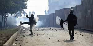 Police officer throw stones towards the supporters of Imran Khan during clashes outside a court in Islamabad on Saturday.