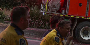 Firefighters take a break near properties where fire retardant was dropped on Barwon Avenue during a fire in South Turramurra.