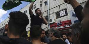 Under a Hamas flag,a demonstrator protests the Israeli bombing of Gaza on the streets of central Ramallah,following Friday prayers.