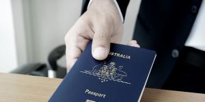 Hands giving passport (of Australia) - dark tone iStock image for Traveller. Re-use permitted. Australian passport generic Australia
