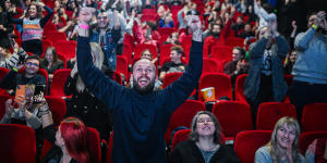 People celebrate as they watch a live screening showing the failed vote of confidence on the Prime Minister Morawiecki cabinet during a parliament session at the Kinoteka cinema in Warsaw.
