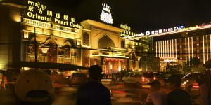 Cambodian motorbike and tuk tuk drivers wait for customers outside the Oriental Pearl Casino and the Gobo East Casino in Sihanoukville in 2018.