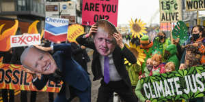 Protesters wearing masks of Boris Johnson and Joe Biden protest outside the entrance to the COP26 site in Glasgow on Friday.