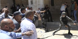Flashpoint:An Israeli border policeman swings their batons at Muslim worshippers outside the Dome of the Rock Mosque in the Al-Aqsa Mosque compound in Jerusalem on Friday. 
