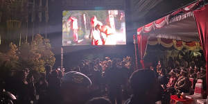 Onlookers watch vision of the Bali bombing aftermath on a big screen at the 20th anniversary memorial of the event in Kuta,Bali.