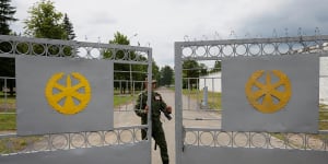 A Belarusian service member closes the gates of a disused base housing a tent camp set up for Wagner but unoccupied.