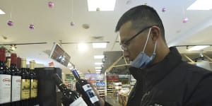 A man compares two bottles of Australian wine at a supermarket in Hangzhou in east China’s Zhejiang province.