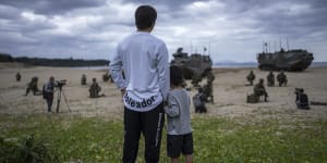 Tatsuya Shimobaba and his son,Eito,watch an amphibious landing exercise in Tokunoshima. A shrinking,agding population in Japan poses an obstacle as the nation tries to counter security threats from China and North Korea.