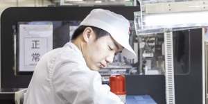 An employee seals a box on the assembly line of a Huawei mobile phone plant in Dongguan,China.
