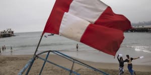 A Peruvian flag flies on the beach in Chorrillos,Lima,as a couple dances on the sand. More than 250 Chinese fishing vessels are operating just outside Peru's maritime zone.