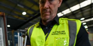 A Border Force officer inspects illegal cigarettes in a shipping container.