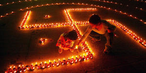 Children light lamps in the shape of the swastika on the eve of Hindu festival of Diwali.