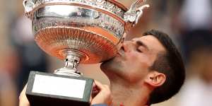 Novak Djokovic kisses the French Open trophy for a third time.