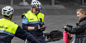 Senior Constable Paul Nichols writes an infringement notice for a rider not wearing a helmet on Monday.