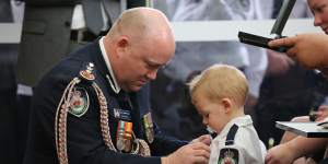 RFS Commissioner Shane Fitzsimmons pins the service medal of Geoffrey Keaton onto his son,Harvey.