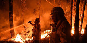 Firefighters work to prevent a blaze from crossing the Kings Highway near Batemans Bay.