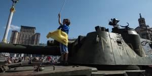A boy holds a Ukrainian national flag on a captured Russian tank in central Kyiv.